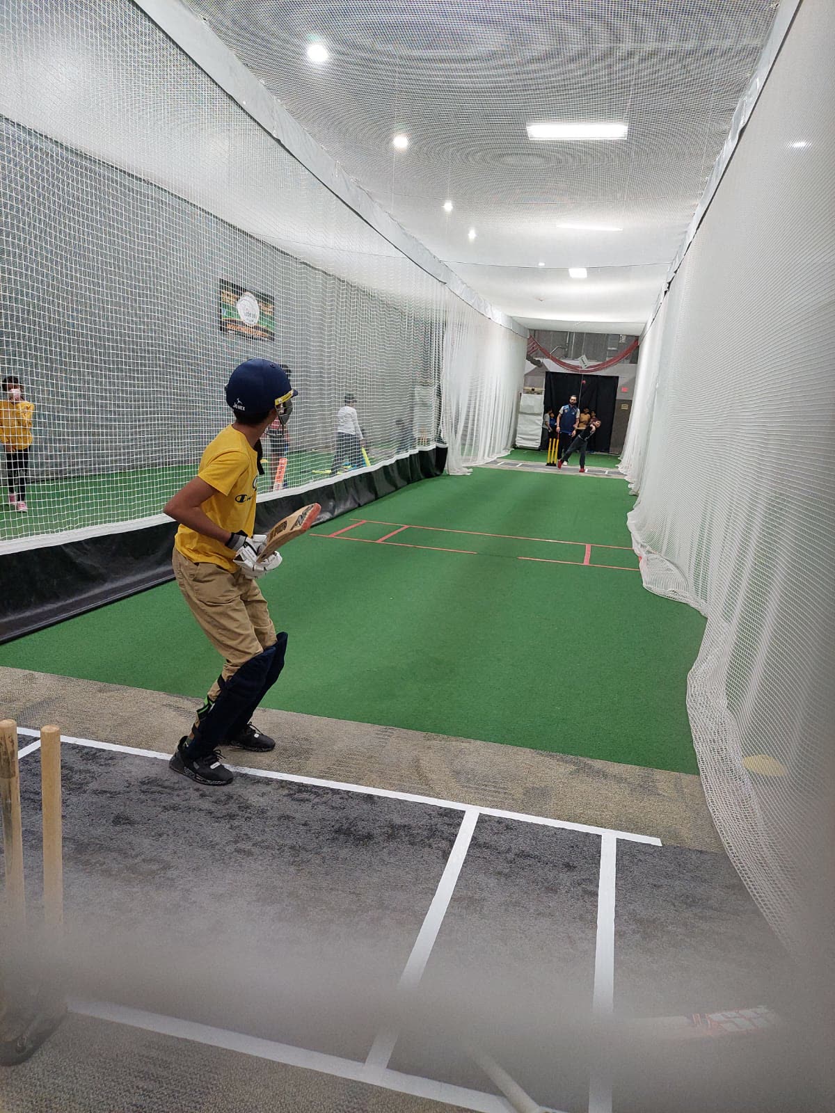 Young beginner batting in an indoor cricket lane at Revolution Cricket Academy in Sterling, VA